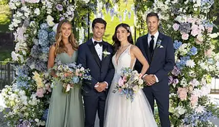 A group of teens with vibrant tuxedos and dresses in prom