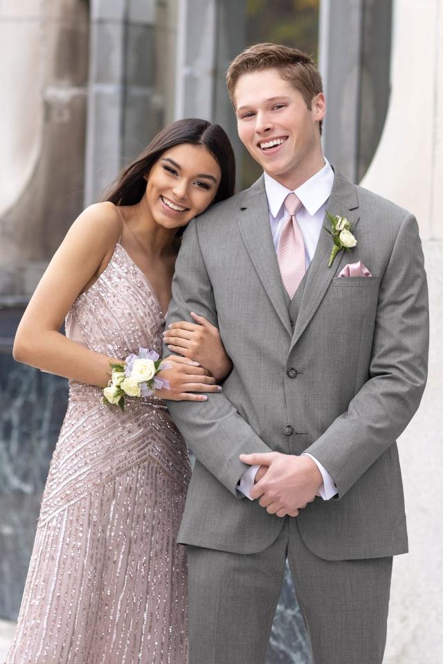 man in Michael Kors Medium Grey suit and blush colored windsor tie standing next to woman in formal blush dress